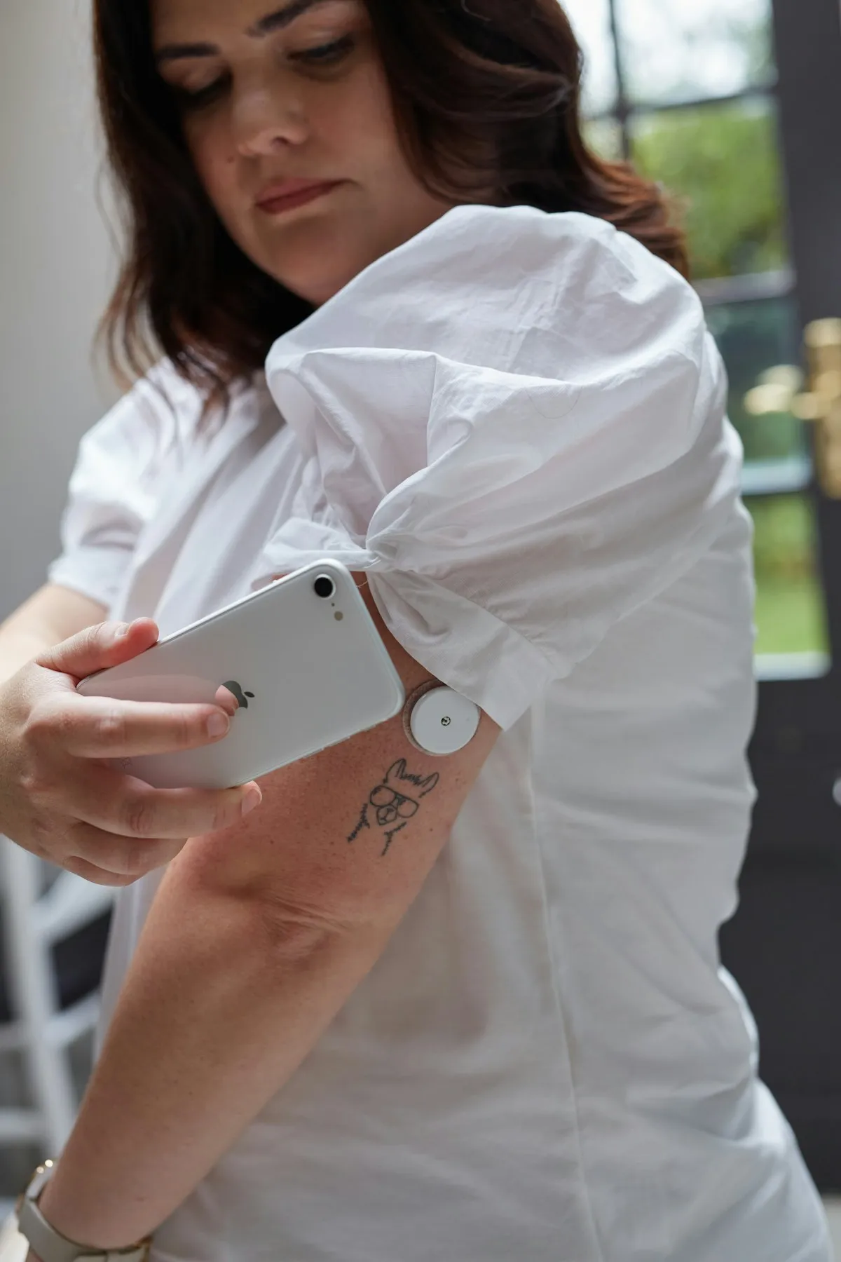 Woman scanning a continuous glucose monitor sensor on her upper arm with a smartphone