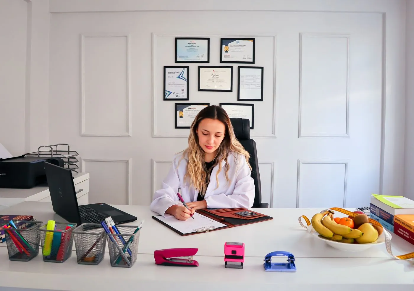 Registered dietitian writing a personalized nutrition plan at her desk with fresh fruit nearby